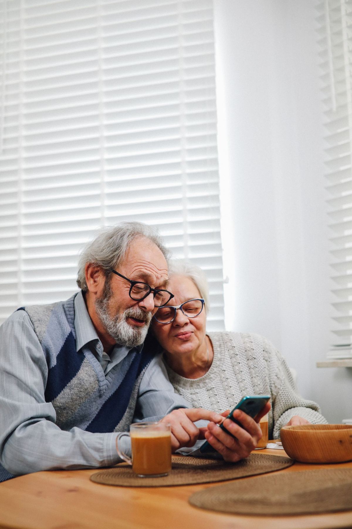 Two older adults sharing coffee and a phone screen