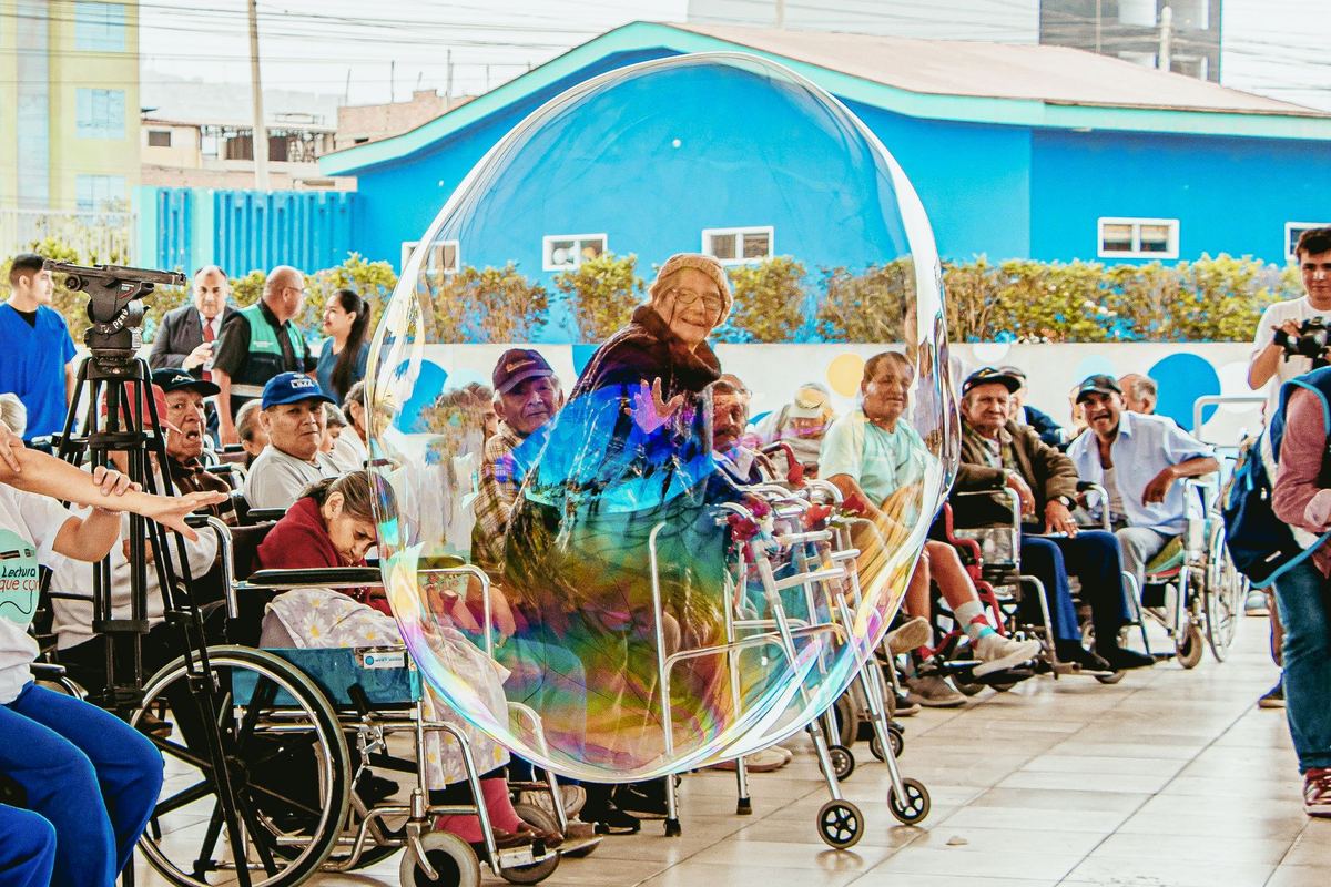 Residents gathered outdoors watching a giant soap bubble drift past
