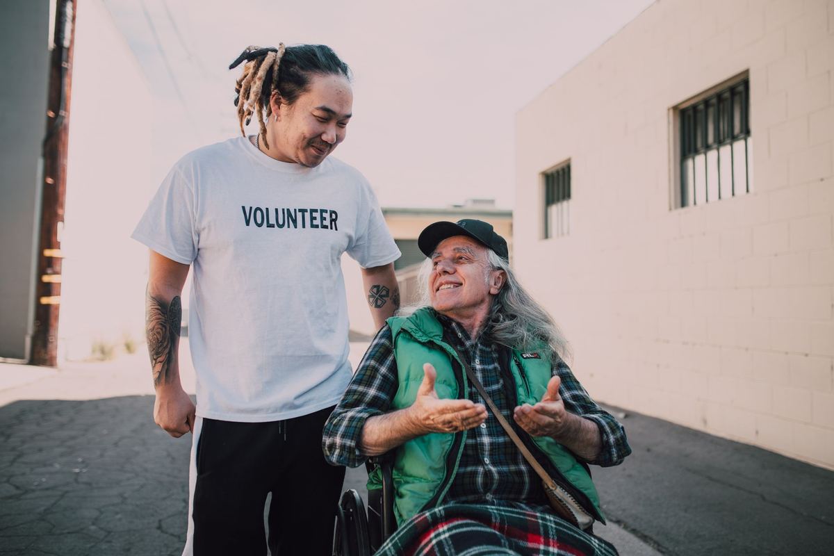 A volunteer laughing with an older man outdoors